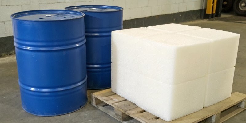 Two chemical drums labeled "Polyol A" and "Isocyanate B" pointing towards a block of finished PU foam