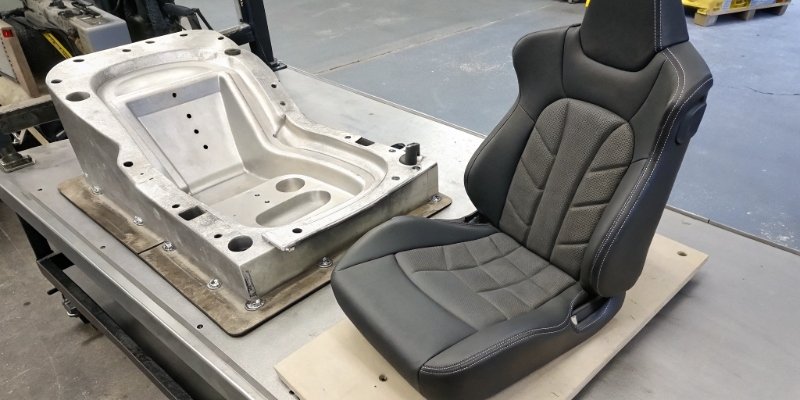 An example of a complex moulded foam car seat next to the metal mold it was made in.