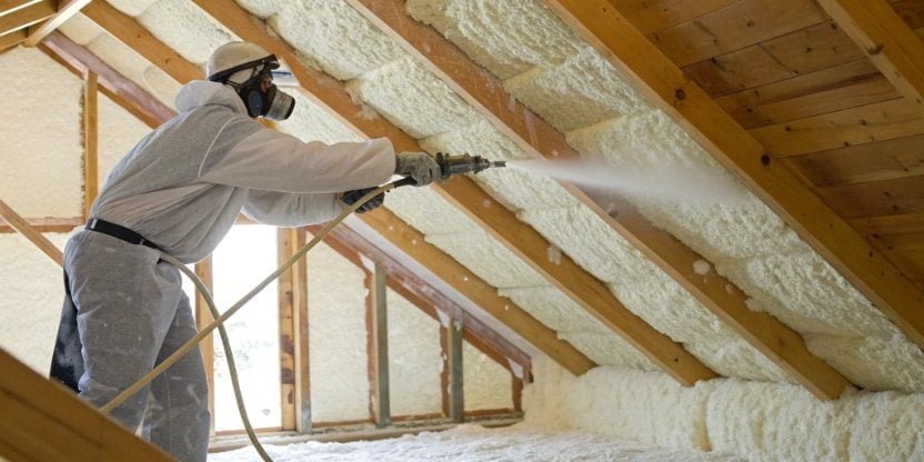 A professional installer spraying foam insulation in an attic
