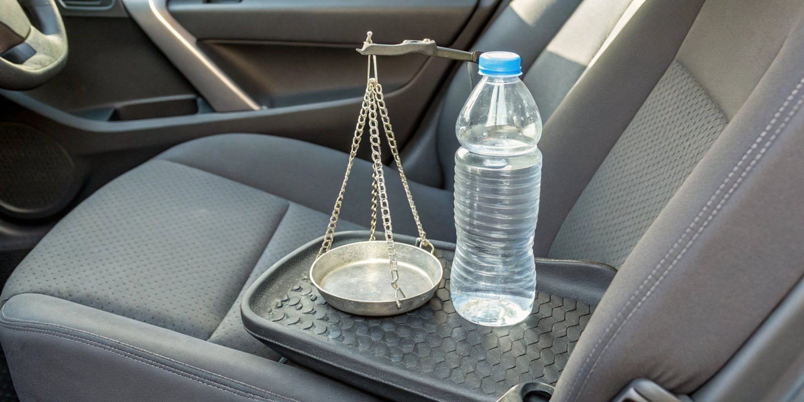 A scale balancing a car seat cushion on one side and plastic bottles on the other.