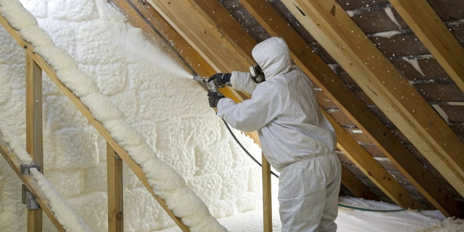 Spray Foam Insulation Application A worker in a hazmat suit applying spray foam insulation to an attic